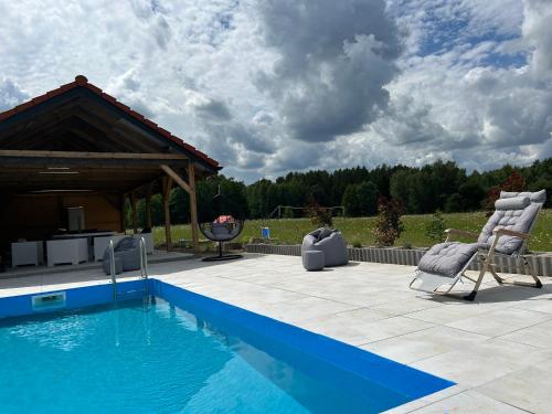 a swimming pool with two chairs and a gazebo at Koniec Świata Stare Sady apartament in Mikołajki