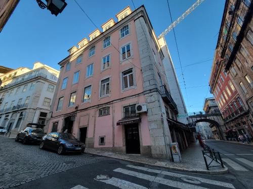 ein rosafarbenes Gebäude an der Straßenseite in der Unterkunft Boho Guesthouse - Rooms & Apartments in Lissabon