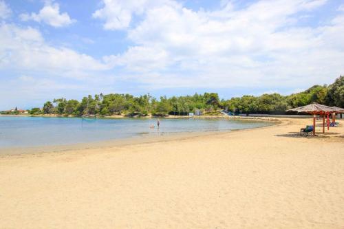 a sandy beach with an umbrella and the water at App 5 Zaton beach Sonnenterrasse Fußbodenheizung einzigartig auch im Herbst und Winter in Zaton