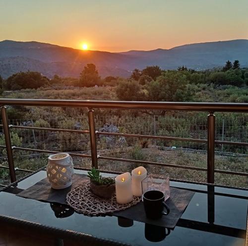a table with candles on top of a balcony with the sunset at Stone villa Halepa panoramic view, private pool,big garden & quiet in Néon Khoríon