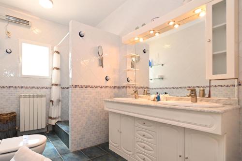 Baño blanco con lavabo y espejo en Casa Ceba, en Jávea