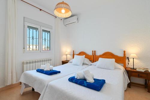 Dos camas en un dormitorio blanco con toallas azules. en Casa Ceba, en Jávea