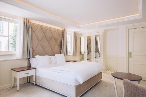 a bedroom with a large white bed and a table at Heritage Grand Perast By Rixos in Perast