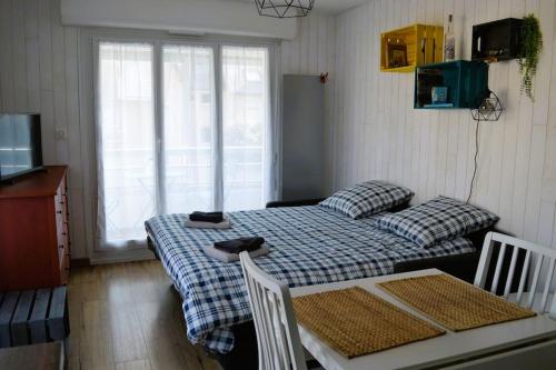 a small room with a bed and a table and a tv at Le petit Courseulles - entre le port et la mer in Courseulles-sur-Mer