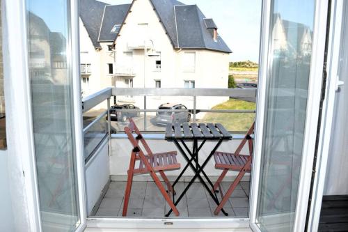 a patio with two chairs and a table on a balcony at Le petit Courseulles - entre le port et la mer in Courseulles-sur-Mer