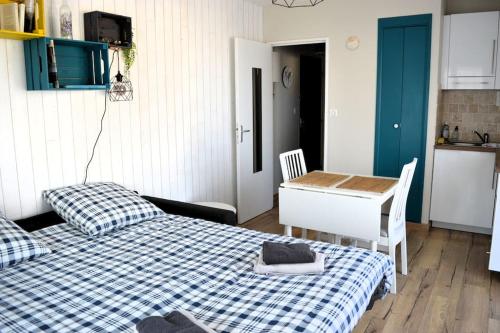 a bedroom with a bed and a desk and a kitchen at Le petit Courseulles - entre le port et la mer in Courseulles-sur-Mer