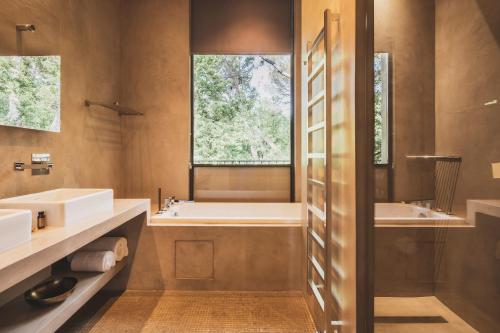 a bathroom with two sinks and a tub and a window at Les Lodges Sainte-Victoire Hotel & Spa in Aix-en-Provence
