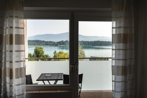 a room with a view of a lake seen through doors at Hotel Faaker See Inn by S4Y in Faak am See
