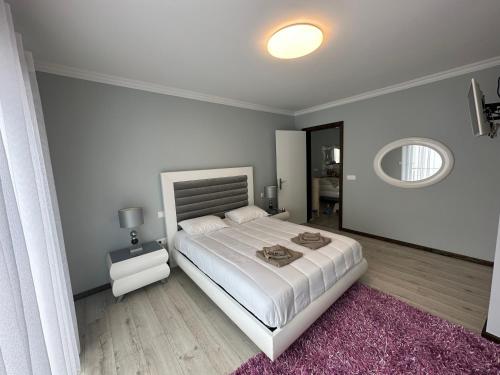 ein weißes Schlafzimmer mit einem großen Bett und einem Spiegel in der Unterkunft The Spot - ilha de São Miguel (Povoação) Açores in Povoação