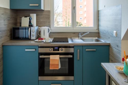 eine Küche mit blauen Schränken, einem Herd und einer Spüle in der Unterkunft hochwertiges Studio in bester Lage in Friedrichshafen