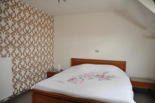Schlafzimmer mit einem Bett mit weißer Bettwäsche und rosa Blumen in der Unterkunft B&B Waterfields in Zonnebeke