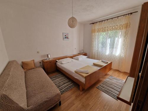 a small bedroom with a bed and a couch at Apartmani Arija in Promajna