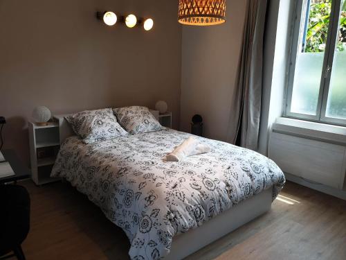a bedroom with a bed with a white comforter and a window at Chez Cerise in Tournay