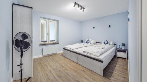 a white bedroom with a large bed and a window at Apartamenty Sun & Snow Helski Zakątek in Hel