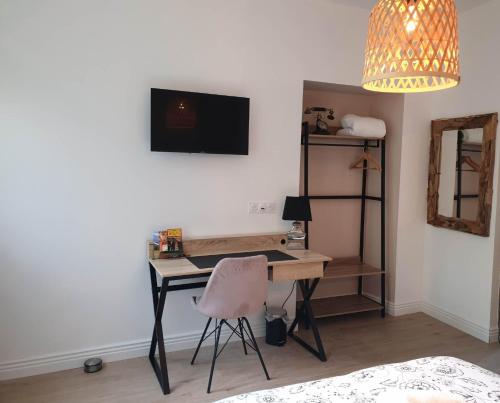 1 dormitorio con escritorio con silla y TV en Chez Cerise, en Tournay