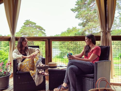 two women sitting in chairs on a porch at Camping du Lac in Marcillac-la-Croisille
