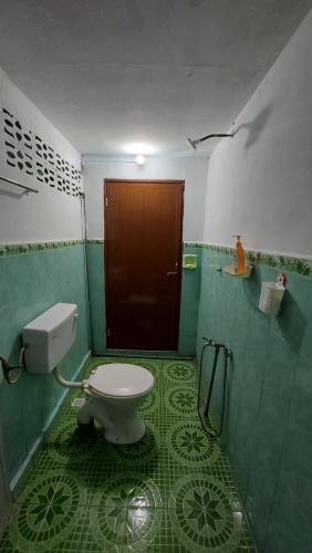 a bathroom with a toilet and a brown door at SEROJA HOMESTAY in Baling