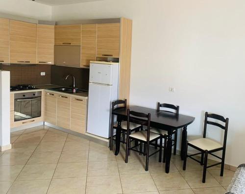 eine Küche mit einem Tisch und Stühlen sowie einem weißen Kühlschrank in der Unterkunft H Apartment Vlorë in Vlorë