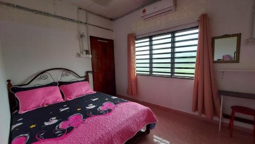 1 dormitorio con cama con sábanas rosas y ventana en SEROJA HOMESTAY, en Baling