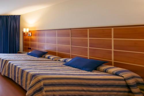 a large bed with blue pillows in a room at Ramblas Vendrell in El Vendrell