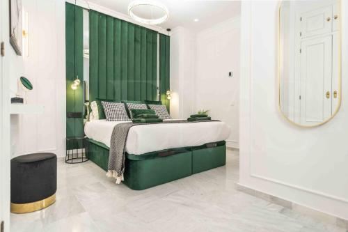 a bedroom with a bed with a green headboard and a mirror at NEW Deluxe Apartment - Historic Center by REMS in Málaga