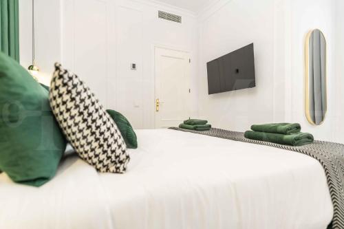 a white bed with green pillows and a tv on the wall at Deluxe Apartment - Historic Center by REMS in Málaga