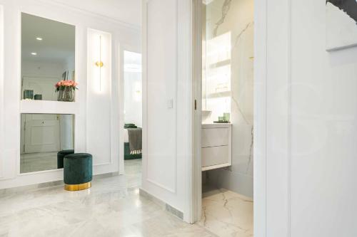 a white hallway with a mirror and a stool at Deluxe Apartment - Historic Center by REMS in Málaga