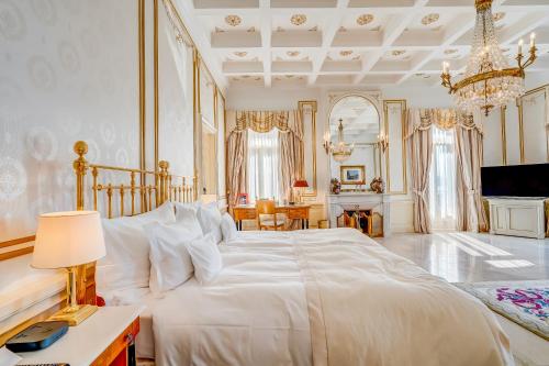 a bedroom with a large white bed and a chandelier at Grand Hotel National Luzern in Luzern