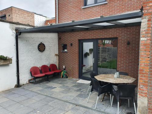 a patio with red chairs and a table in front of a building at Private Room with shared spaces in Ranst