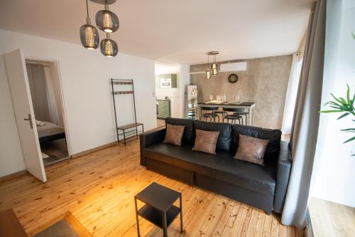 un salon avec un canapé noir et une table dans l'établissement LA FABRIQUE - Centre ville - Climatisation, à Saint-Étienne