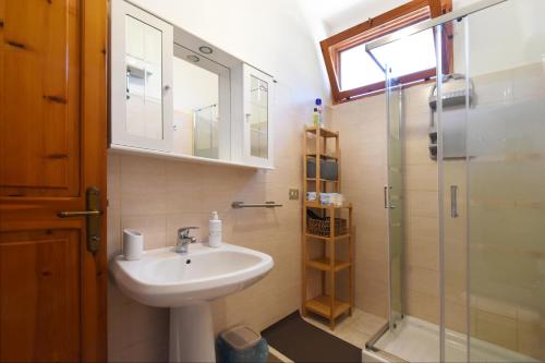 uma casa de banho com um lavatório e uma cabina de duche em vidro. em Mario & Nina - Portopino House em Porto Pino