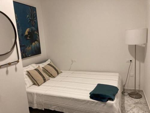 uma cama num quarto branco com uma toalha azul em Piso Cádiz Centro Histórico em Cádiz