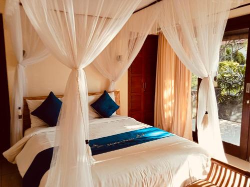 a bedroom with a bed with white curtains and a window at Shankara Parada Villas in Amed