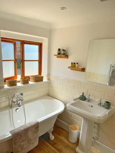 a bathroom with a white tub and a sink at Barons Granary , The Bull Pen in Iden