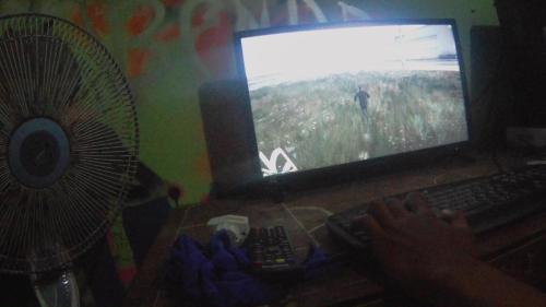 una persona jugando un videojuego en un ordenador con un ventilador en Pemandangan sungai opak, en Pundung