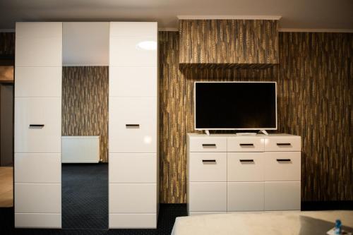 a living room with a television and a white dresser at Hotel Epic Centrum in Cisnădie
