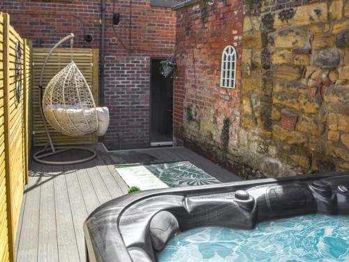a bath tub in a courtyard with a brick wall at Stunning Town Center Cottage with hot tub in Morpeth