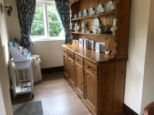 a kitchen with wooden cabinets and a window at Forda Farm Bed & Breakfast in Holsworthy
