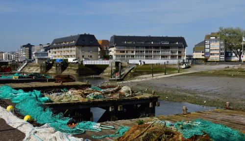 a river with nets and buildings in a city at Le petit Courseulles - entre le port et la mer in Courseulles-sur-Mer