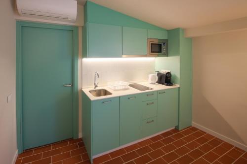 una cucina con mobili blu e un lavandino di Terra Aurea Aparthotel a Salou
