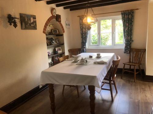 a dining room with a white table and a window at Forda Farm Bed & Breakfast in Holsworthy