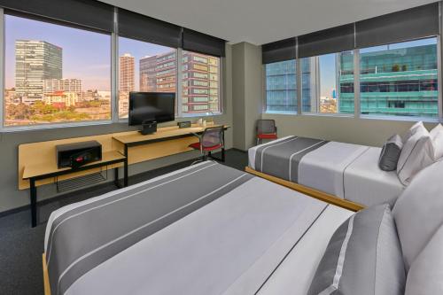 a bedroom with two beds and a desk with a tv at City Express Plus by Marriott Ciudad de México Santa Fe in Mexico City
