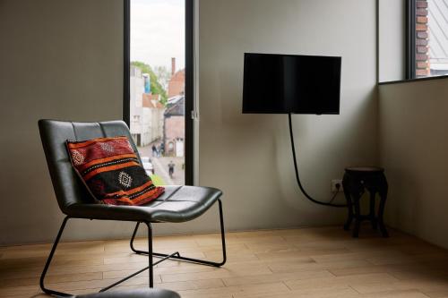 a chair with a pillow and a television in a room at Business Guesthouse in Groningen