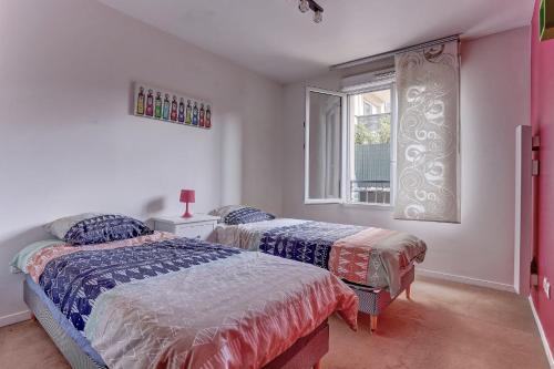 2 camas en un dormitorio con ventana en Le Montespan- Saint Cyr, en Saint-Cyr-lʼÉcole