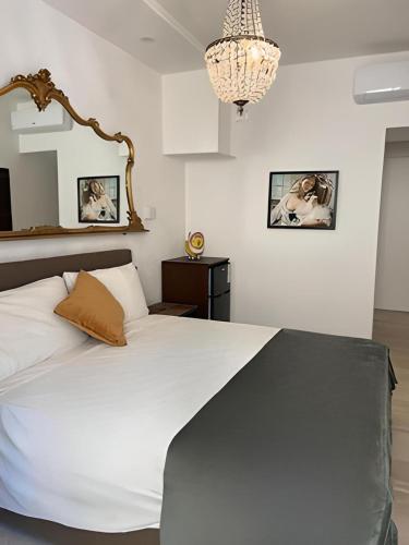 una camera da letto con un grande letto bianco e un lampadario a braccio di La Dimora Degli Angeli a Noto