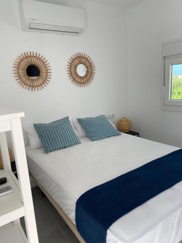 a white bed with blue pillows and mirrors on the wall at CH II Apartments ZONA DE OCIO NOCTURNO in Conil de la Frontera