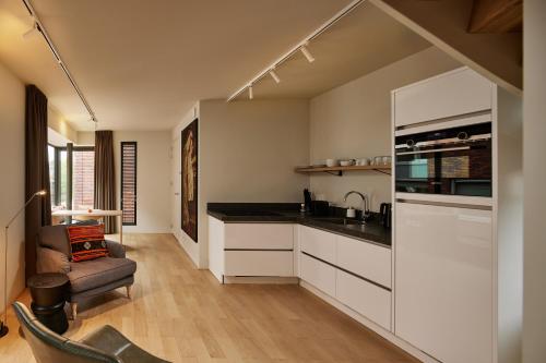 a kitchen with white cabinets and black counter tops at Business Guesthouse in Groningen