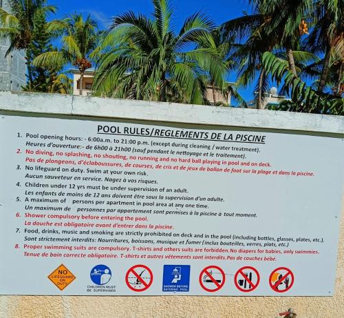 a sign on a beach with palm trees in the background at The Coastal Apartment in Flic-en-Flac