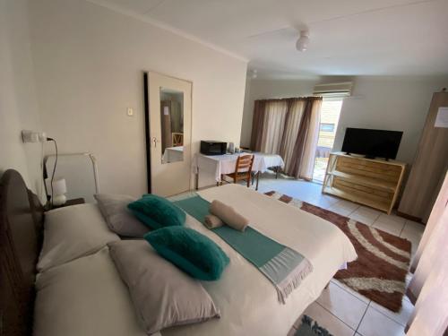 ein Schlafzimmer mit einem großen weißen Bett mit grünen Kissen in der Unterkunft El-Kole Bed and Breakfast in Tsumeb