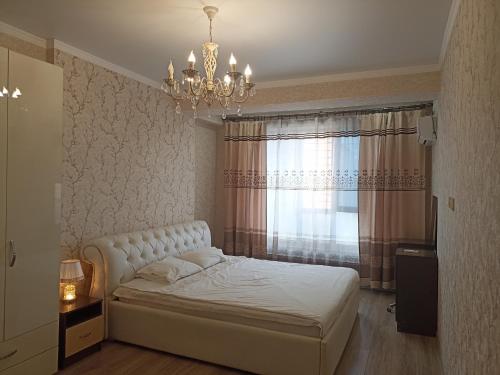 ein Schlafzimmer mit einem weißen Bett und einem Kronleuchter in der Unterkunft Orion Apartment in Bischkek